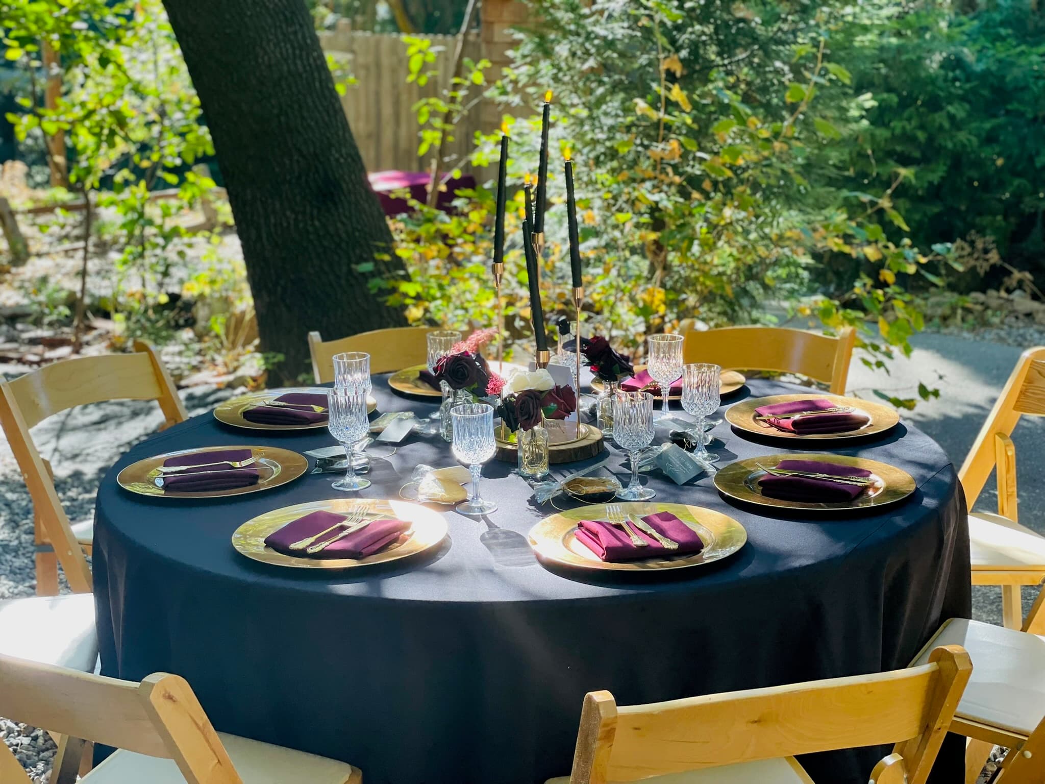 A candlelit table set for a private dinner under the trees
