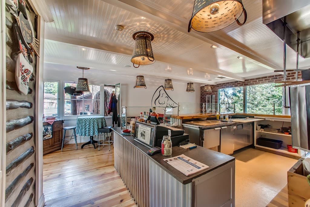 Inside LouEddie's: the order counter under colander lamps, a log wall and a checkered table by the window